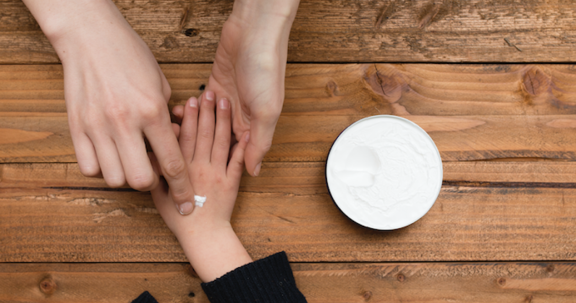 adult hands applying lotion on child's hand