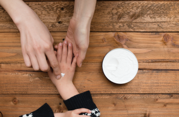 adult applying lotion on child's hand